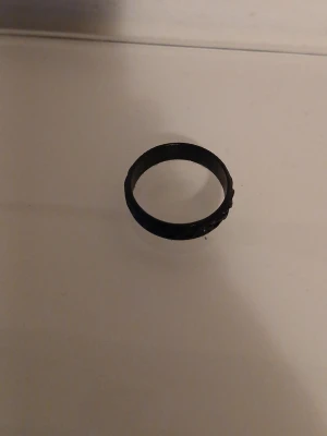 Svart ring i enkel design - En stilren svart ring med slät yta och rund form. Ringen har en enkel och modern look utan några extra detaljer eller dekorationer. Passar dig som gillar minimalistiska accessoarer. Materialet ser ut att vara plast eller resin.