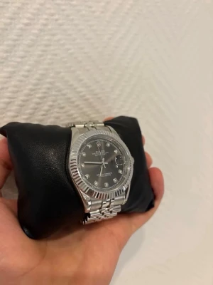 R*l3x klocka (Silver & Grå urtavla) - Jag säljer min helt nya R*l3x klocka som är i färgen silver & har en grå urtavla med Diamantindex. Denna modell heter Datejust och klocka är i väldigt fint skick!                                  Hör av dig vid intresse!