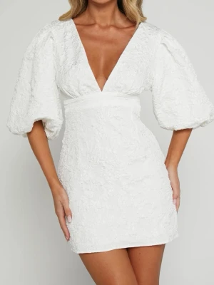 Studentklänning showpo - Kort vit klänning med djup v-ringning och puffiga trekvartsärmar. Klänningen har en markerad midja och struktur i tyget som ger en exklusiv känsla. Använd men har inge som helst tecken på att den använts. Säljer då jag köpte den för att ha den som studentklänning men nu har hittat en annan. Den är i storlek 35 men skulle säga att den lägger sig väldigt fin även fast man har 34.