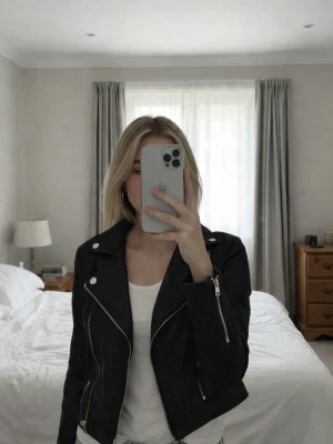 Svart jacka med dragkedjor - Snygg svart jacka med silvriga dragkedjor och knappar. Klassisk bikerstil med bred krage och två fickor framtill. Perfekt för en cool och trendig look.