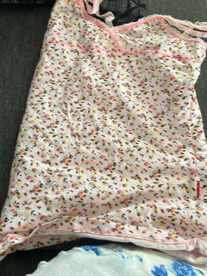 Blommigt nattlinne från Claesens - Sött nattlinne från Claesens i ljusrosa med små blommor i rosa, gul och svart. Tunna axelband och spetsdetaljer upptill ger en gullig look. Perfekt för mysiga kvällar hemma.