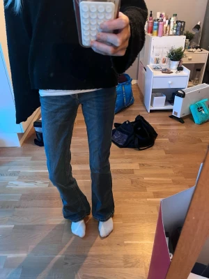 Mörkblå bootcut jeans - Säljer ett par mörkblå bootcut jeans med klassisk femficksdesign och normal midja. Jeansen har en tidlös tvätt och raka ben som går ut lite nedtill. Perfekta för dig som gillar en avslappnad men ändå snygg stil.