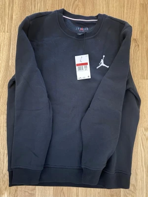 Svart Jordan hoodie med logga - Svart hoodie från Jordan med den klassiska Jumpman-loggan broderad i vitt på bröstet. Tröjan har rund halsringning och ribbade muddar vid ärmar och nederkant. Tillverkad i mjuk bomullsblandning för maximal komfort.