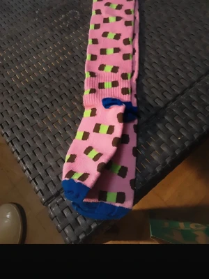 Färgglada mönstrade strumpor - Säljer ett par långa strumpor i rosa med gröna, bruna och svarta blockmönster. Tån och hälen är blå för en extra färgklick. Perfekta för dig som gillar att sticka ut med dina accessoarer!stödstrumpor