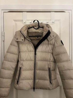 Beige jacka från Save The Duck - Beige dunjacka från Save The Duck i S/XS, luvan går att ta av! Vatten resistant och varm så perfekt till höst/vinter. Nypris 2200kr
