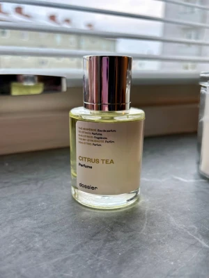 Citrus Tea parfym från Dossier - Fräsch parfym från Dossier med namnet Citrus Tea. Flaskan är rund och genomskinlig med en silverfärgad kork och enkel, modern etikett. Doften har tydliga citrusnoter och en hint av te, perfekt för dig som gillar lätta och uppfriskande parfymer. 50ml endast testad 