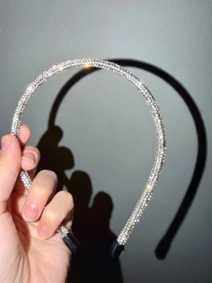 Glittrigt diadem med strassdetaljer - Snyggt diadem täckt av glittrande strass i silverfärg. Diademet är smalt och flexibelt med svarta ändar för extra komfort bakom öronen. Perfekt accessoar för att lyfta din look med lite extra bling.