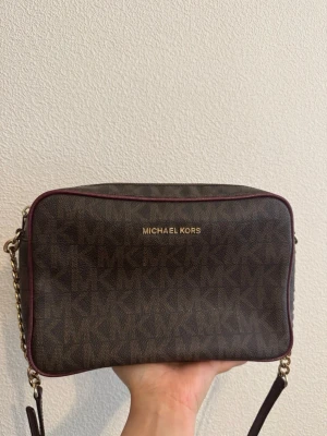 Brun/burgundy  axelväska Michael Kors - Säljer min snygga bruna/burgundy axelremsväska från Michael Kors givetvis är den original därav priset. Den är använd se foton! Men är givetvis i acceptabelt skick till användning :) 💕 