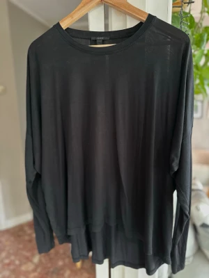 Svart långärmad topp från COS Medium - En stilren svart långärmad topp från COS med rund halsringning. Tillverkad i ett tunt, mjukt material som ger en avslappnad och loose passform. Perfekt att styla lager på lager eller bära som den är. Använd men i bra skick 