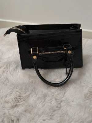 Glansig handväska med gulddetaljer  - Aldrig använd!