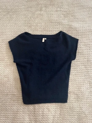 Stickad topp - En enkel och stilren mörkblå stickad topp från Nelly. Toppen är offshoulder/sneaxlad, croppad passform och är ärmlös med bred halsringning. 