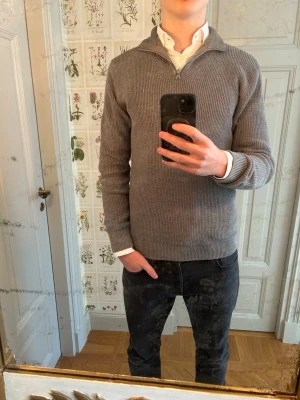 Grå stickad tröja med halvzip - Säljer en stilren grå stickad tröja med halvzip och hög krage från Qubus!🔥 Vanlig passform och look som funkar för alla årstider!👌🧊Perfekt att bära över en skjorta för en snygg lager-på-lager-look men kan också stylas lätt med en t-shirt. Hör av er vid minsta fundering!📌😎