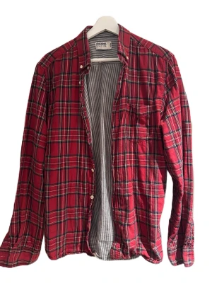 Dobber flanell skjorta  - En nichad flanell skjorta från Dobber i storlek M samt färg röd. Skick 7/10 skjortan är lite mer vintage, men den är sparsamt använd, små defekter förekommer. Kom dm för fler frågor osv!