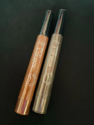 Helt ny - 1 st 4-Tip Brow ögonbrynspenna grå eller brun - Gäller 1 st helt NY ögonbrynspenna, modell 4-Tip Brow. Ena pennan är ljusbrun och den andra är gråton. Pennorna har en speciell 4-tip applikator för att skapa naturliga brynstrån och är tillverkade i plast med genomskinliga lock. Vill man köpa båda så är priset 179:-