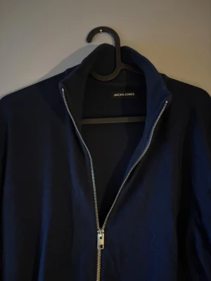 Mörkblå fullzip  - Säljer min mörkblå fullzip från Jack & Jones i storlek M, tröjan har en normal passform. Den passar till allt och är perfekt nu till våren! Använd några gånger och är i bra skick. Pris kan diskuteras vid snabb affär🙌