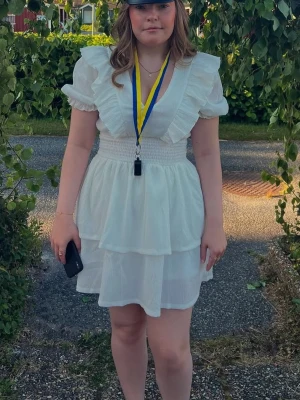 Studentklänning från Gina Tricot - Säljer nu min fina studentklänning. Den är fortfarande i fint skick. Perfekt klänning om man vill ha en enklare men fin på utspringet. Det går även bra att ha ett par vita cykelbyxor under då den har volanger och inte blir genomskinlig. 