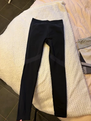Svarta träningstights Cross Sportswear - Säljer ett par svarta träningstights från Cross Sportswear. De har diskreta mönstrade detaljer längs benen och bred resår i midjan för extra komfort. Perfekta för gymmet eller löprundan, tillverkade i stretchigt funktionsmaterial- går också att använda som underställ. Uppskattning storlek xs