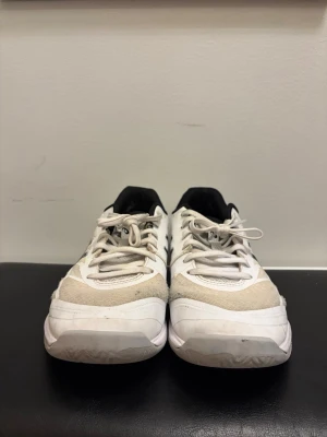 Vita Asics sneakers med svart detalj - Säljer ett par vita Asics sneakers med svarta detaljer och meshpaneler för bra ventilation. Skorna har snörning, låg profil och en slitstark sula som passar perfekt för sport och träning. Klassisk Asics-logga på sidan och bekväm innersula.
