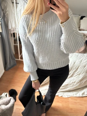 Ljusgrå stickad tröja med ballongärm - Trendig ljusblå stickad tröja med ballongärmar och ribbade muddar. Tröjan har en avslappnad passform och är gjord i ett mjukt, tjockt material som passar perfekt till höst och vinter. Enkel att matcha med både jeans och byxor.