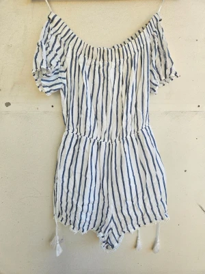 Randig off-shoulder jumpsuit - Blåvitrandig jumpsuit från Bershka i tunt och luftigt tyg som passar perfekt på sommaren. Passar att ha över axlarna eller off shoulder. Storlek S.