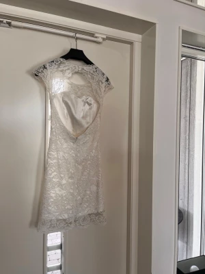 Vit spetsklänning med öppen rygg - Säljer en elegant vit spetsklänning från by Malina med korta ärmar och öppen rygg som stängs med två lärlingsplatser. Klänningen har figurnära passform, inbyggda kupor och fina spetsdetaljer över hela plagget. Endast använd två dagar under studenten. Storlek xs samt inga defekter eller missfärgningar.  Nypris 2400kr
