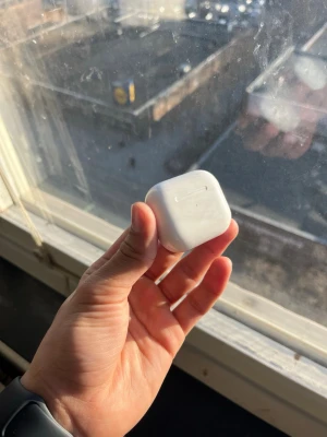 Vita trådlösa hörlurar i laddningsetui - Säljer ett par vita trådlösa hörlurar med tillhörande laddningsetui. Etuiet är kompakt och har en slät, blank yta med rundade kanter. Perfekt för dig som vill ha smidiga hörlurar att ta med överallt.