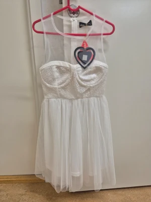 Vit kort klänning med meshdetaljer - Supersöt vit kort klänning från Nelly med mesh upptill och vadderad byst. Kjolen är i 1 lager tunn tyll.