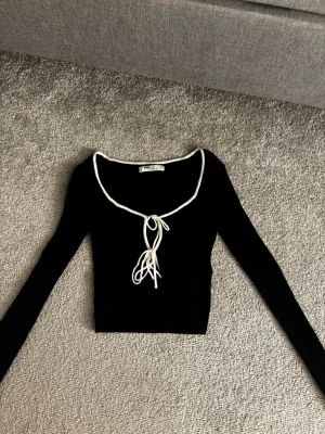 svart långärmad topp med snörning - svart långärmad topp i ett ribbat material med vit knytning och u ringning ifrån new yorker! aldrig använt🩷kontakta för fler bilder eller frågor! 
