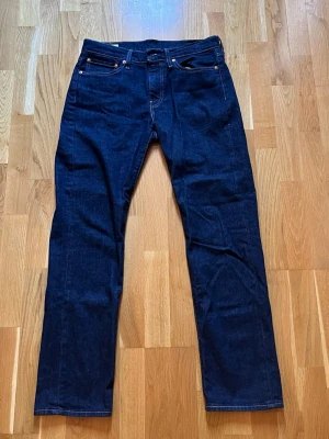 Mörkblå raka jeans från Levi's - Snygga mörkblå jeans från Levi's med klassisk rak passform och fem fickor. Jeansen har tydliga kontrastsömmar och en läderpatch bak i midjan. Perfekta för en stilren och tidlös look. Tillverkade i slitstark denim.