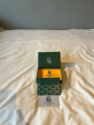 G&yard plånbok - Snygg grön korthållare från G@yard med det klassiska mönstret i vitt och grått comparison på canvasmaterial. Kommer med original ask och certifikat. Perfekt för kort och ID, smidig att ha i fickan och riktigt stilren accessoar.