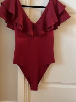 Vinröd body - Vinröd body med volanger. Jag köpte den för länge sedan och har klippt bort lappen så vet inte vart den är ifrån. Fint skick 🥰