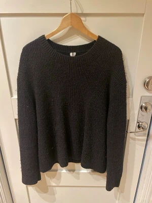 Svart stickad tröja från Arket - En svart stickad tröja från Arket. Tröjan har en klassisk, rak passform och är ribbstickad för en stilren look. Perfekt för lager-på-lager och enkel att matcha med olika outfits. Storlek M. Material: Ull