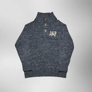 Vintage Abercrombie & Fitch grovstickad 1/4 button up tröja - herr strl L  - Säljer en vintage Abercrombie & Fitch grovstickad 1/4 button up tröja i grå färg med guldiga detaljer i storlek L med broderi “A&F” på vänster sida av bröstkorgen.  👕 Märke: Abercrombie & Fitch 📏 Storlek: L 🎨 Färg: Grå 📐 Mått: 69 cm lång, 54 cm bred 📌 Skick: Mycket bra skick (se bilder)  💬 Hör av dig vid frågor 💰 Pris kan diskuteras vid snabb affär 📦 Skickas inom 24 timmar
