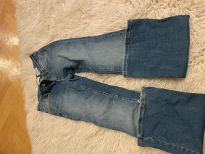 Blå utsvängda jeans från ONLY XS - Säljer ett par blå jeans från ONLY i storlek XS. Jeansen har en cool utsvängd modell med markerad söm vid knäna och klassisk femficksdesign. Tillverkade i denim med ljusare tvätt på låren och mörkare nedtill. Perfekta för en trendig look.