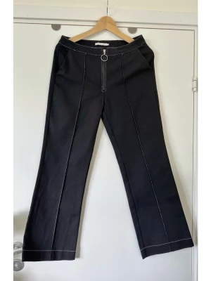 AÉRYNE - Svarta utsvängda jeans med kontrastsömmar - storlek S - Stilrena svarta jeans / byxor från franska modehuset Aéryne i storlek S. Tidlös modell med lätt vida / utsvängda ben och vita kontrastsömmar och pressveck. Iögonfallande dragkedja framtill med ringdetalj. Snyggt markerade pressveck framtill. Stabilt vävt tyg i 95% bomull och 5% viskos, så bra naturmaterial som andas. Unika kvalitetsbyxor och designerjeans som passar till allt. Nypris 3600:-. Mycket gott skick, som nya!