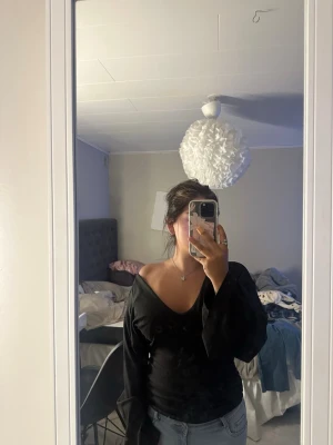 Svart offshoulder topp med v-ringning - Trendig svart topp med offshoulder-design och djup v-ringning. Långärmad modell i mjukt material som sitter snyggt på kroppen.  storlek S från shein 