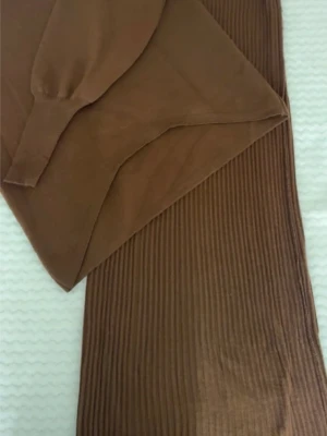 Brun stickad set med tröja och kjol - Säljer ett brunt stickat set med långärmad tröja och matchande ribbad kjol. Tröjan har rund hals och långa ärmar med ribbade muddar. Kjolen är midilång och har vertikala ribbor för en snygg struktur. Perfekt för dig som gillar en enkel men trendig look.