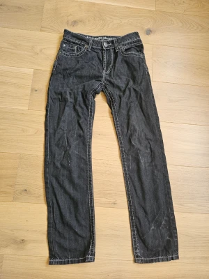 Svarta jeans med vita sömmar - Snygga svarta jeans med raka ben och kontrasterande vita sömmar. Klassisk femficksmodell och låg midja. Perfekta för en avslappnad och cool stil.