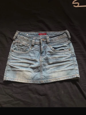 Lågmidjad jeanskjol  - Supersöt vintage jeanskjol som är lågmidjad och har coola detaljer på bakfickorna! Midjemåttet är 36 cm och den är 30 cm lång💕💕