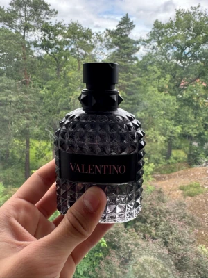 Valentino born in Roma parfym - Ca 75% kvar. Säljer en lyxig parfym från Valentino i en genomskinlig glasflaska med coolt nitmönster och svart etikett. Flaskan har en svart kork med detaljer som ger en edgy känsla. Perfekt för dig som gillar exklusiva dofter och snygg design. Innehåller ej boxen.