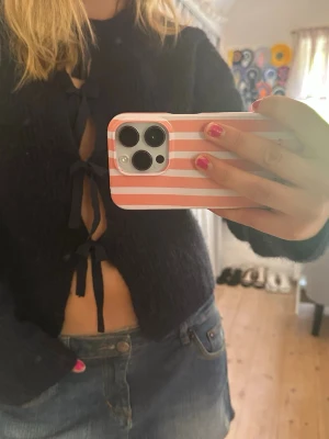 Marinblå kofta med rosetter - Snygg blå kofta med tre rosetter framtill. Koftan är lite kortare i modellen och har långa ärmar. Perfekt att styla med jeans eller kjol för en trendig look.