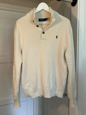 Beige stickad tröja Polo Ralph Lauren - Snygg beige stickad tröja från Polo Ralph Lauren med klassisk krage. Tröjan har ribbade muddar och nederkant. Perfekt till jeans eller chinos. Perfekt för sommaren. Mint condition. Inga defekter.☀️🛥️