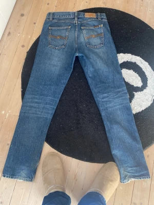 Blå raka jeans från Nudie Jeans - Säljer ett par klassiska blå jeans från Nudie Jeans med rak passform och fem fickor. Modellen är gritty Jackson som är en lite lösare Lean Dean. W 29 L 32 men waisten är åtminstone w 30 fråga gärna om mått i cm. Dom har lite heel bite men som jag personligen bara tycker får dom att se snyggare ut se bild 4.