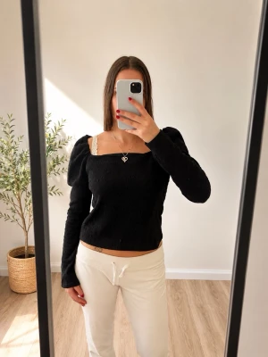 Svart långärmad topp från H&M - Trendig svart långärmad topp från H&M med fyrkantig urringning och lätt puffade axlar. Toppen har en smickrande slim passform och är tillverkad i ett mjukt, stretchigt material som sitter snyggt på kroppen.