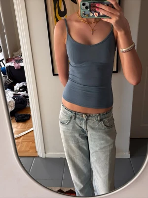 Blå linne - Snygg blå linnetopp med smala axelband och ribbad struktur. Toppen har en kroppsnära passform och är perfekt att styla till jeans eller kjol. Enkel och stilren design utan synliga loggor.