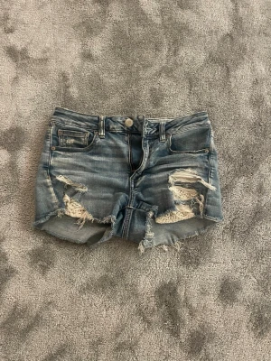 Blå slitna jeansshorts med fransar - Snygga blå jeansshorts från Silver Jeans Co. Är använda en del, men ändå i fint skick! Storlek 36 