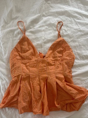 Orange randig linnetopp med tunna band - Snygg orange linnetopp med tunna axelband och vita smala ränder. Toppen har v-ringad hals och ett lätt utställd, flowy passform nedtill. Perfekt för varma dagar och sommarens alla äventyr. Toppen är från Zara och är i storlek XS! Packas och postas säkert! 💓