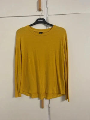 Gul stickad tröja Gina Tricot - Mysig gul stickad tröja från Gina Tricot med rund halsringning och lång ärm. Tröjan har en enkel, loose passform och är perfekt för lager på lager. Passar till både jeans och kjol för en avslappnad look.
