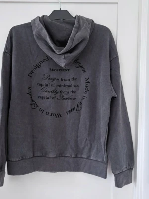 Grå oversize hoodie med ryggtryck och gråsyratvättad look, M, NY - Gråsyra tvättad huvtröja med dragkedja och en tvättad look. Tröjan har en stor ficka framtill och muddar vid ärmslut och nederkant.   Nypris 539kr. 