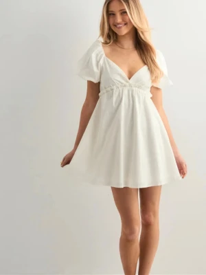 Vit kort puffärmad klänning - Supersöt vit kort klänning med puffärmar och djup v-ringning. Klänningen har en omlott-effekt upptill och markerad midja med lätt rynk. Perfekt för sommarens alla tillfällen och ger en romantisk vibe. Från Nelly i stl 34, helt ny med prislapp kvar. Köpt för 400